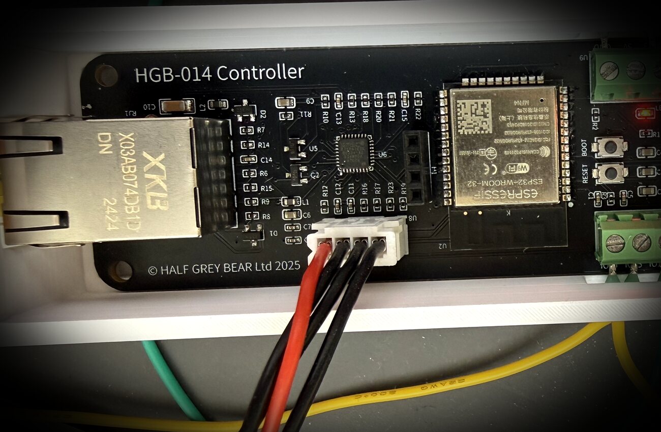 A custom black circuit board labelled HGB-014 Controller, © Half Grey Bear Ltd 2025, with an ESP32 module, Ethernet jack and DMX terminals.
