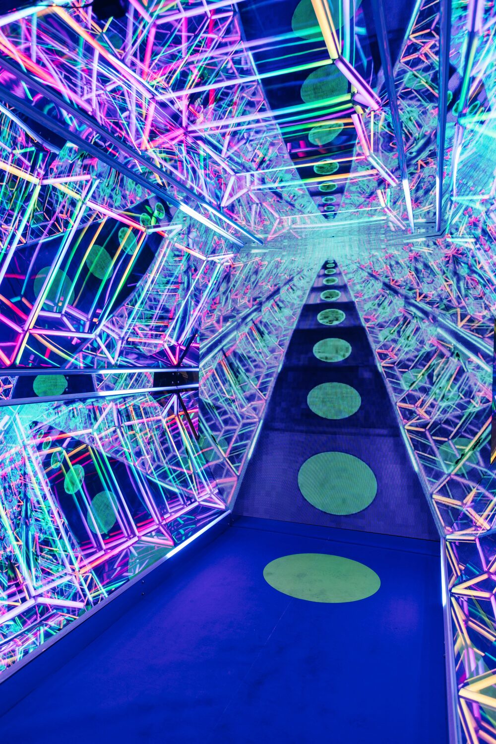 Inside the Infinity Cave — a mirrored corridor of multicoloured LED lattices with glowing stepping dots receding forever.
