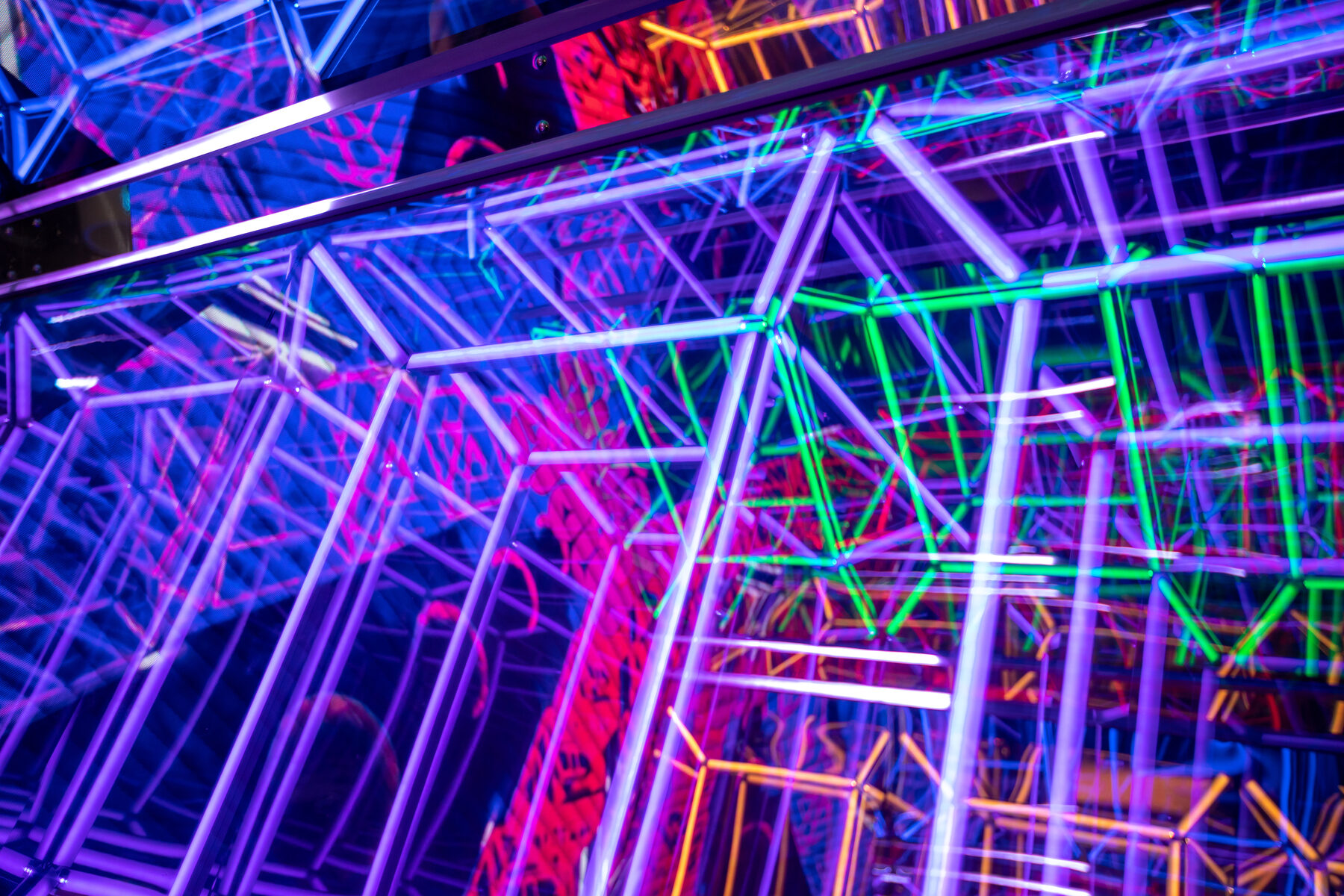 Abstract detail inside the Infinity Cave — lattices of multicoloured LED lines repeating into the mirrors without end.