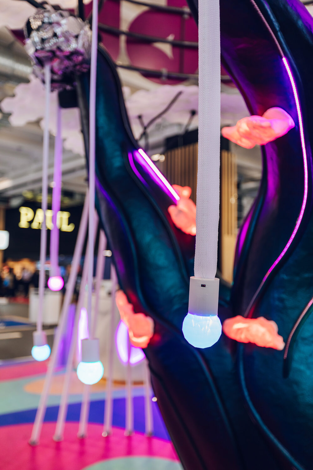 Close-up of the hanging light-ball tendrils — faceted glowing spheres on white cords against the dark trunk.