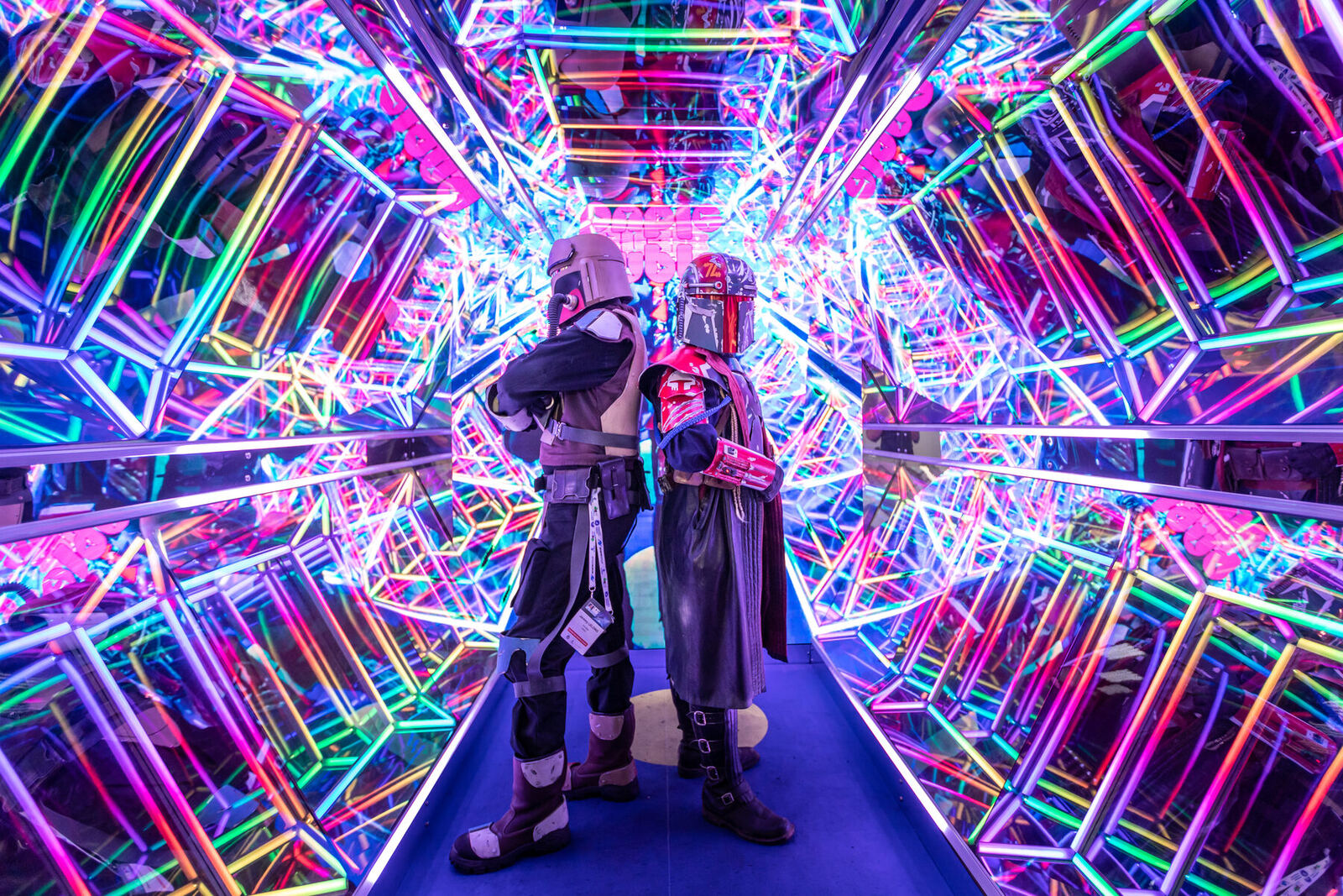 A mirrored, pixel-mapped neon tunnel forming an infinite kaleidoscopic corridor of coloured light.