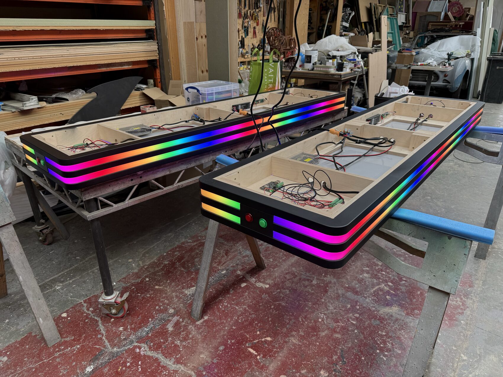 The two tables mid-build in the workshop, rainbow pixel tape already alive along their edges.