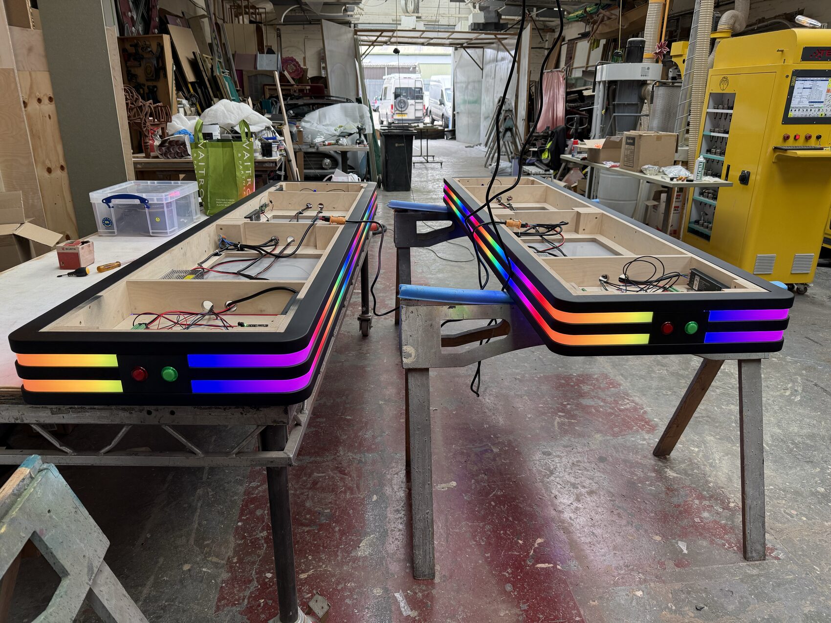 Both tables open on the bench, wiring and electronics bays visible inside, edge LEDs glowing.