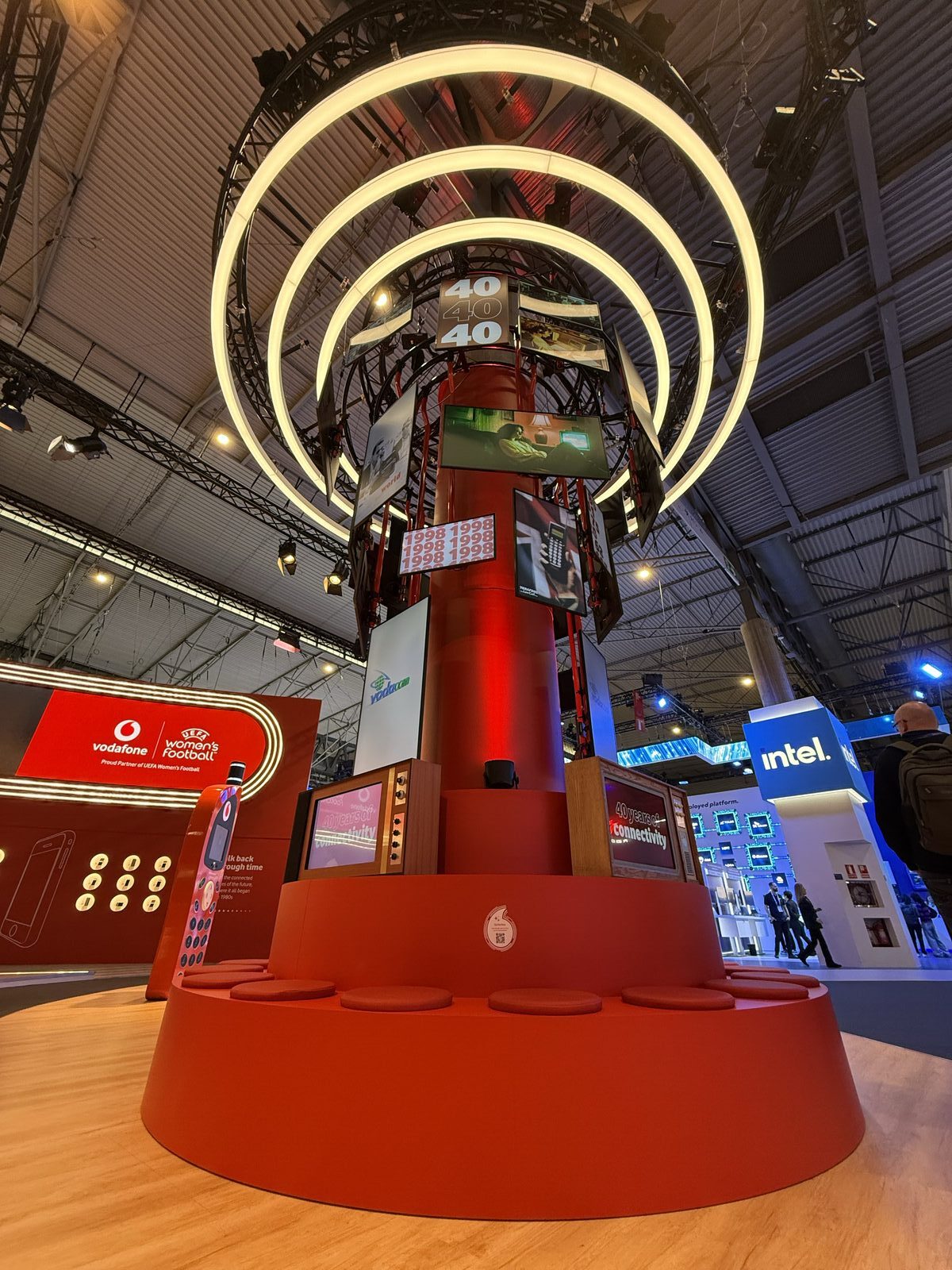 The six-metre tornado attractor — thirty screens spiralling up a red tower beneath ring lights, with the retro TV cases built into its base.