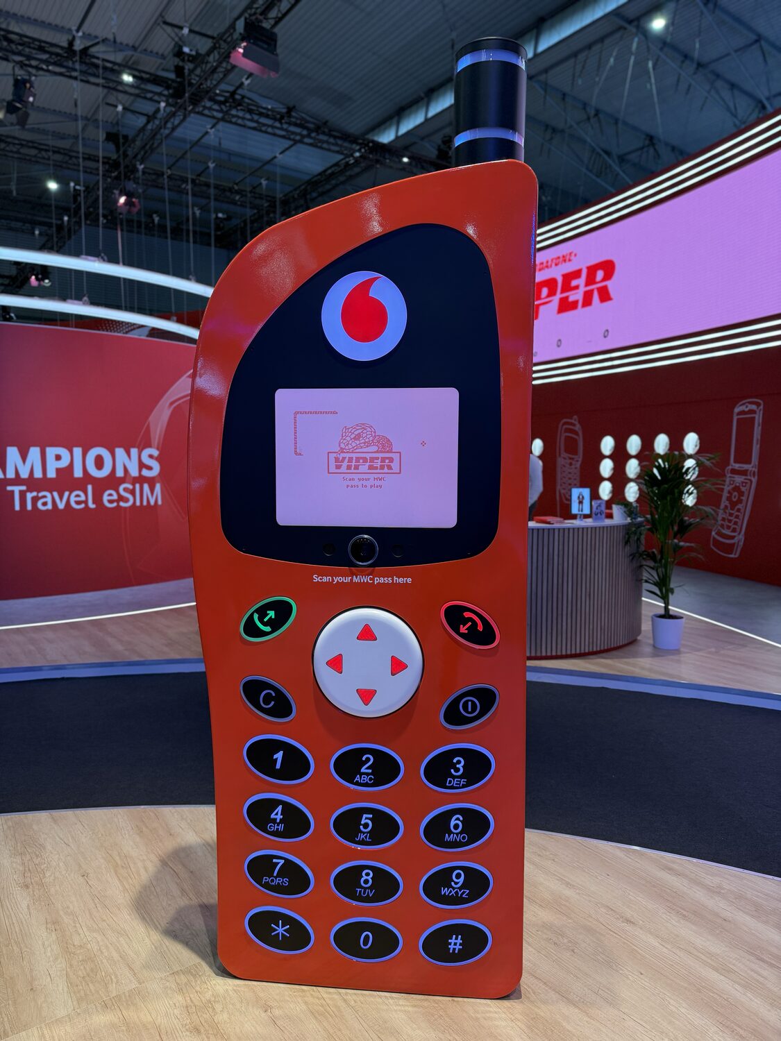 Viper in full — a person-sized red Vodafone retro phone with the game on its colour screen, a backlit keypad and an antenna, on the stand at Mobile World Congress 2026.